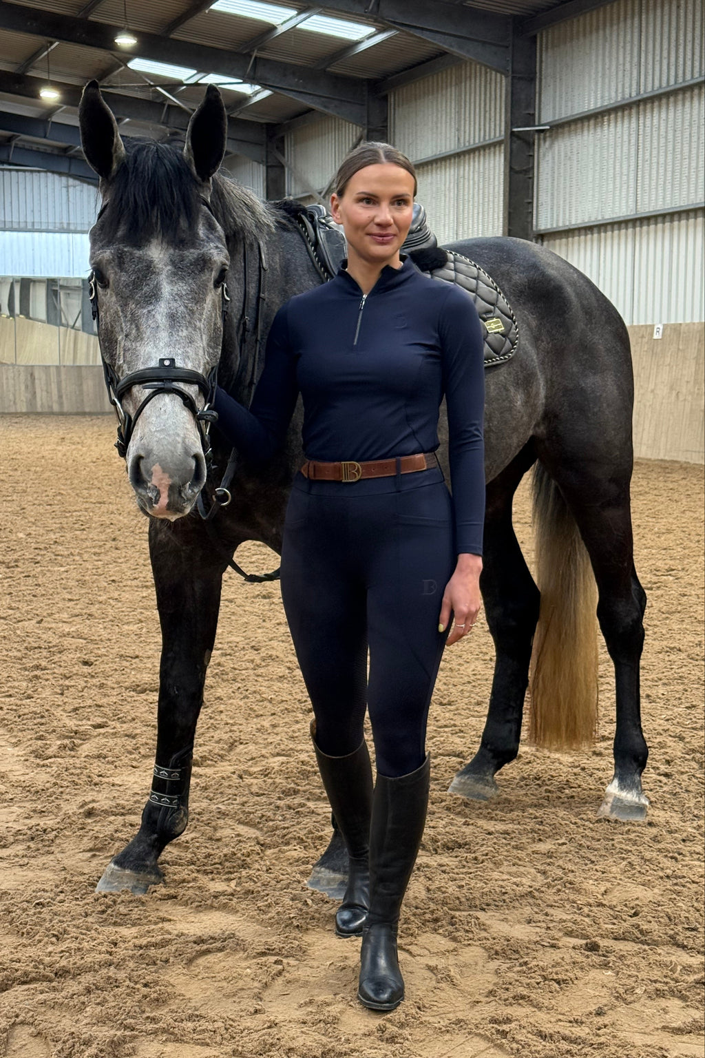 Person standing next to a horse in an indoor arena
